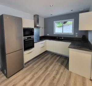 a kitchen with white cabinets and a stainless steel refrigerator at Appartement cosy au calme in Hasparren