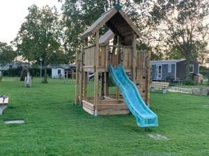 a wooden playground with a slide in a yard at Lieblingsplatz Renesse, Camping Siblu de Oase in Renesse