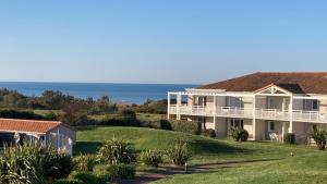 een groot huis met de oceaan op de achtergrond bij Les Sables-d'Olonne - Vue Mer, Terrasse, Wifi Fibre & Piscine, à 2 pas de l'Océan - E101 in Les Sables-dʼOlonne