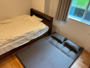 a bedroom with a bed and a couch next to a window at Roycoできたばかりでとても綺麗な宿です黒豚しゃぶしゃぶの有名店近く in Kagoshima