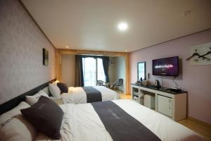 統営市にあるDorcas Tourist Hostelのベッド2台、薄型テレビが備わるホテルルームです。