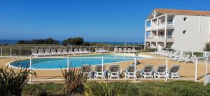 een zwembad met ligstoelen en een gebouw bij Les Sables-d'Olonne - Vue Mer, Terrasse, Wifi Fibre & Piscine, à 2 pas de l'Océan - E101 in Les Sables-dʼOlonne