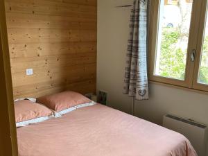 a bed with two pink pillows in a room with a window at Appartement confortable au Grand-Bornand pour 5 personnes - FR-1-467-146 in Le Grand-Bornand