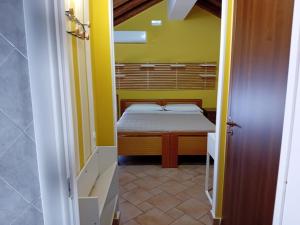 una piccola camera con un letto in una camera gialla di Casa Happy - La mansarda del sorriso con parcheggio privato a Valcorrente a Belpasso
