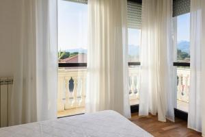 a bedroom with white curtains and a large window at GOLDEN LUXE - Royal Sea View Private Parking in Marina di Pietrasanta
