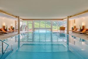 a large swimming pool with blue water in a building at Hotel Klausnerhof - Hintertux in Tux