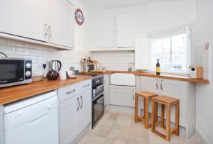 a white kitchen with white cabinets and wooden counter tops at The Davey Tower, Medieval Riverside House in York