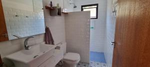 a white bathroom with a sink and a toilet at Recanto na Mantiqueira - Casa 3Q a 2 km do centro in Gonçalves
