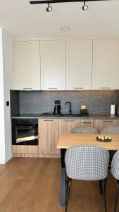 Una cocina con una mesa de madera y gabinetes blancos. en Terra29 apartman, zlatiborski kutak sa besplatnim parkingom, en Zlatibor 35 fotos más