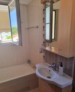 a bathroom with a sink and a mirror and a tub at Onda Blu Deluxe Loutraki in Loutraki