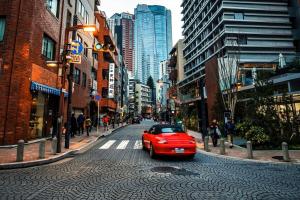 a red car driving down a street in a city at Hotel-Mercurius-Azabujuban-RB in Tokyo