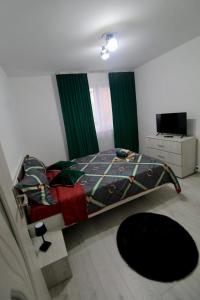 a bedroom with a bed with green curtains and a television at Apartament HD3 in Hunedoara