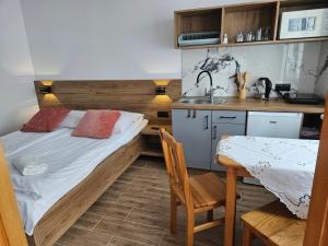 a bedroom with a bed and a kitchen with a table at Pokoje do Wynajęcia u Lusi in Krościenko
