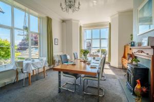 a dining room with a table and chairs and windows at Corner Beech House in Grange Over Sands