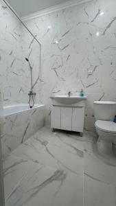 a white bathroom with a sink and a toilet at Новая большая 1-ком кв ЖК Satym мкр Батыс-2 in Aktobe