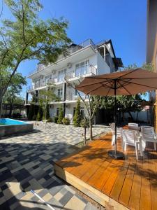 a wooden deck with an umbrella in front of a building at Zatokas Sun Club in Zatoka
