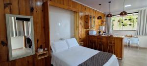 a bedroom with a white bed and a kitchen at Studio Aconchego Correntina in Correntina