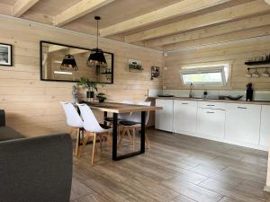 a kitchen with a dining table and white cabinets at Domki Liza in Dziwnów