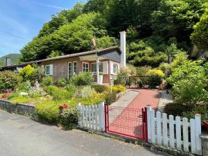 a house with a white fence and a garden at Idyllisches Häuschen im Grünen mit Whirlpool in Roßbach