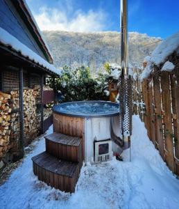 a hot tub in the snow next to a house at Idyllisches Häuschen im Grünen mit Whirlpool in Roßbach