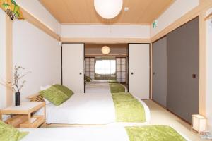 2 letti in una camera con cuscini verdi di 100 square meters up to 11 people Namba Direct Bus 3 mins JR Osaka Loop Line Station 8 mins Train to Namba 12 mins, USJ 30 mins Kyoto Nara OK ad Osaka