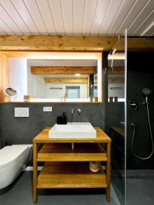 un bagno con lavandino, WC e specchio di Westertilli Eckhuus - modernes, luxuriöses Wohngefühl a Pellworm Altre 20 foto