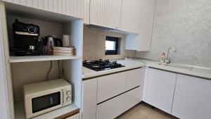 cocina blanca con fogones y microondas en YNS Cozy House, en Iaşi