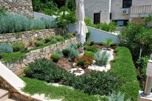 a garden with an umbrella and some plants at Oasis apartment in Selca
