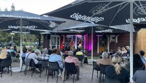 a group of people sitting at tables under umbrellas at Kempingas Zarasai in Zarasai