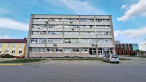 a large building with a car parked in a parking lot at Cozy studio apartment in Marijampolė