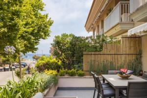a patio with a table and chairs and a fence at SeaBreezeHeaven - Sea View Apartment, Pool & Spacious Terrace with BBQ - 50m from Sant Pol Beach in Sant Feliu de Guixols