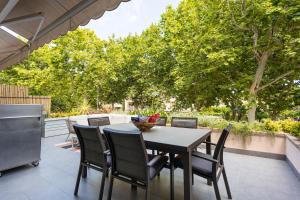 a table and chairs on a patio with trees at SeaBreezeHeaven - Sea View Apartment, Pool & Spacious Terrace with BBQ - 50m from Sant Pol Beach in Sant Feliu de Guixols