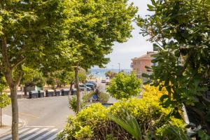 a view of a street with trees and buildings at SeaBreezeHeaven - Sea View Apartment, Pool & Spacious Terrace with BBQ - 50m from Sant Pol Beach in Sant Feliu de Guixols