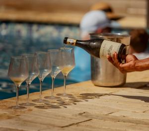 a person pouring wine into a row of wine glasses at Blue Apple Beach in Tierra Bomba