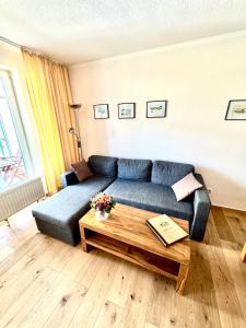 ein Wohnzimmer mit einem blauen Sofa und einem Tisch in der Unterkunft Haus Strandeck Apartment Meeresrauschen 12 in Göhren