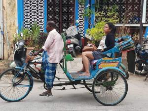 a man pulling a woman on a rickshaw at Villa Butterfly Studio in Pondicherry