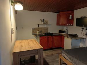 a small kitchen with red cabinets and a wooden table at Tulman Apartment in Balatonberény