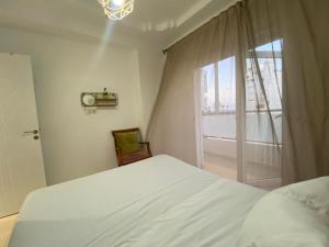 a bedroom with a white bed and a window at Aura Douce Appartement in Martil