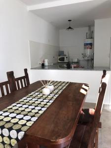 a wooden table with chairs and a kitchen in the background at Duplex en alquiler in Tandil