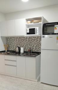 a white kitchen with a microwave and a refrigerator at Sam Lake Towers 2 in Villa Carlos Paz