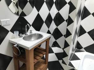 un bagno con lavandino e parete a scacchi in bianco e nero di La Rioja 4880 n1 a La Lucila del Mar Altre 8 foto
