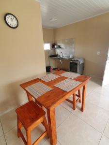 a wooden table in a kitchen with a clock on the wall at Casa de locação in Goiana