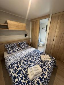 a bedroom with a blue and white bed with two pillows at Nouveau bungalow No 575 Camping 4 étoiles Lac des Rêves in Lattes