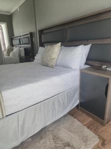 a large bed with white sheets and pillows on it at Villa de Casa in Boksburg +3 photos