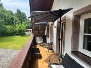 a patio with an umbrella and chairs on a porch at Timos Dahoam 93qm Balkon und familienfreundlich in Nesselwang