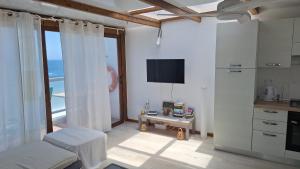 Dieses weiße Zimmer verfügt über einen TV und einen Tisch mit einem Stuhl. in der Unterkunft Eros OceanView Attic in Santa Cruz de Tenerife