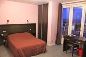 a bedroom with a bed and a desk and a window at Hotel Le Richelieu in Le Tréport