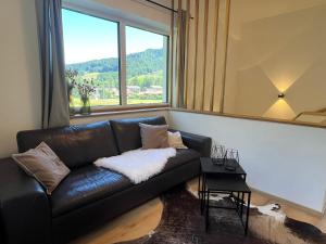 Un sofá de cuero negro en una habitación con una ventana grande. en Servus in der Wiesenstrasse inklusive Chiemgaukarte, en Ruhpolding