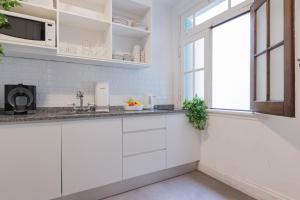 une cuisine avec des armoires blanches et une fenêtre dans l'établissement Fliphaus Ravignani 2200 - Vintage Villa Palermo Hollywood, à Buenos Aires