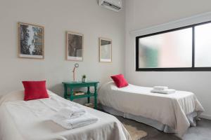 - une chambre avec 2 lits dotés d'oreillers rouges et d'une fenêtre dans l'établissement Fliphaus Ravignani 2200 - Vintage Villa Palermo Hollywood, à Buenos Aires
